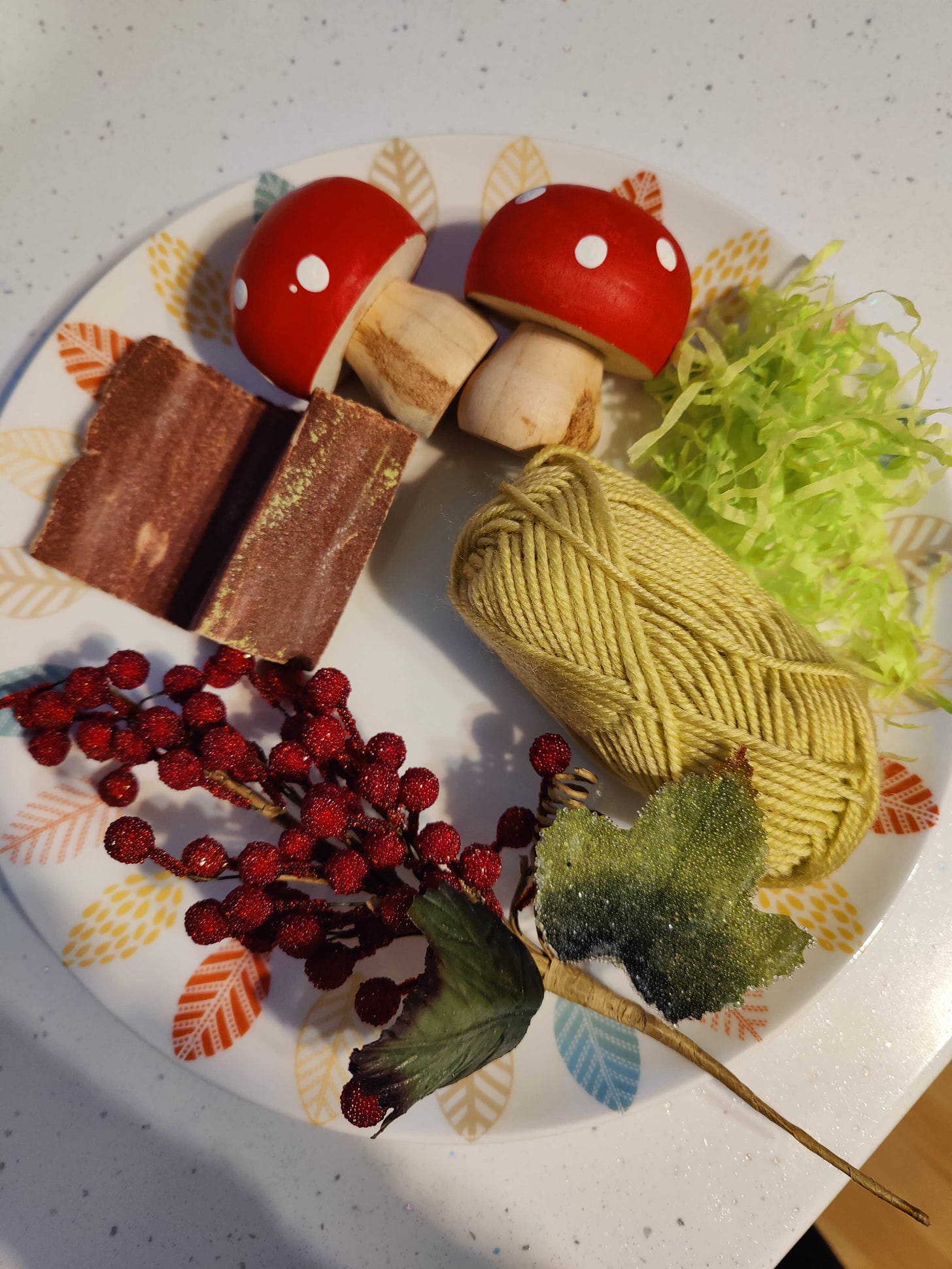 The image is a plate filled with objects found around the house that look like real food. It includes wood mushroom, brown sandpaper, berries, a ball of knitting yearn and some green paper