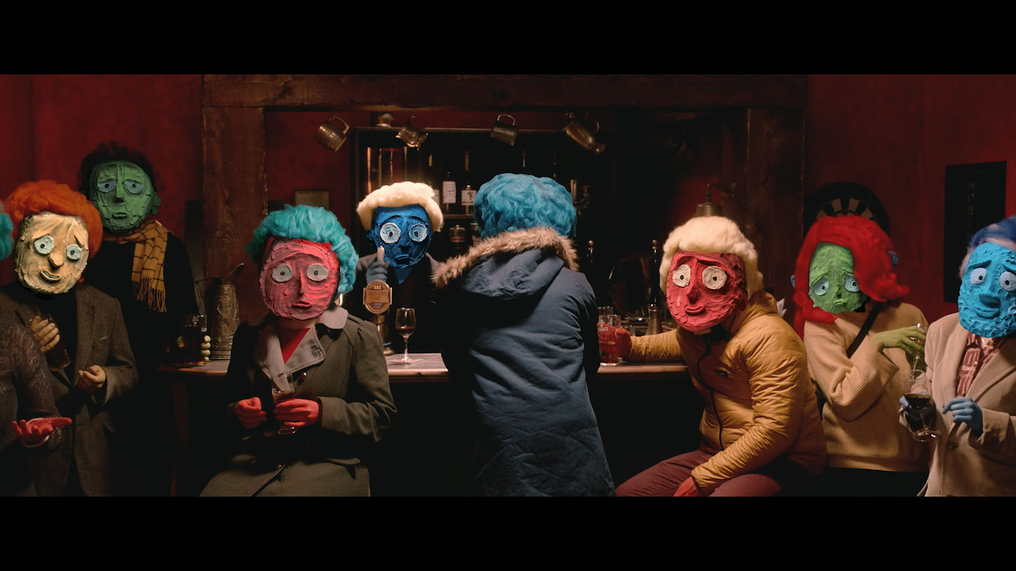 Screenshot from Sam Gainsborough's short film Facing It. Shows people with claymation faces sitting at a bar, staring directly down the camera at the viewer.