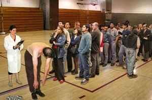 Photo of people standing in line inside a gym for scoliosis testing