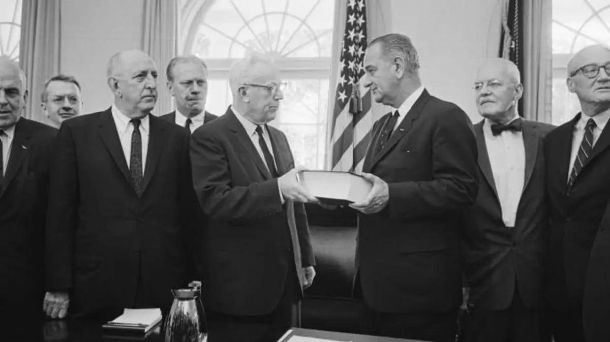 This image shows Chief Justice of the Supreme Court Earl Warren (third from left) presenting the Warren Commission's final report to President Lyndon B. Johnson inside the White House. The Commission's six other members flank both men. This image shows Chief Justice of the Supreme Court Earl Warren (third from left) presenting the Warren Commission's final report to President Lyndon B. Johnson inside the White House. The Commission's six other members flank both men.
