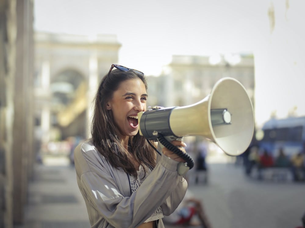 Free Cheerful young woman screaming into megaphone Stock Photo
