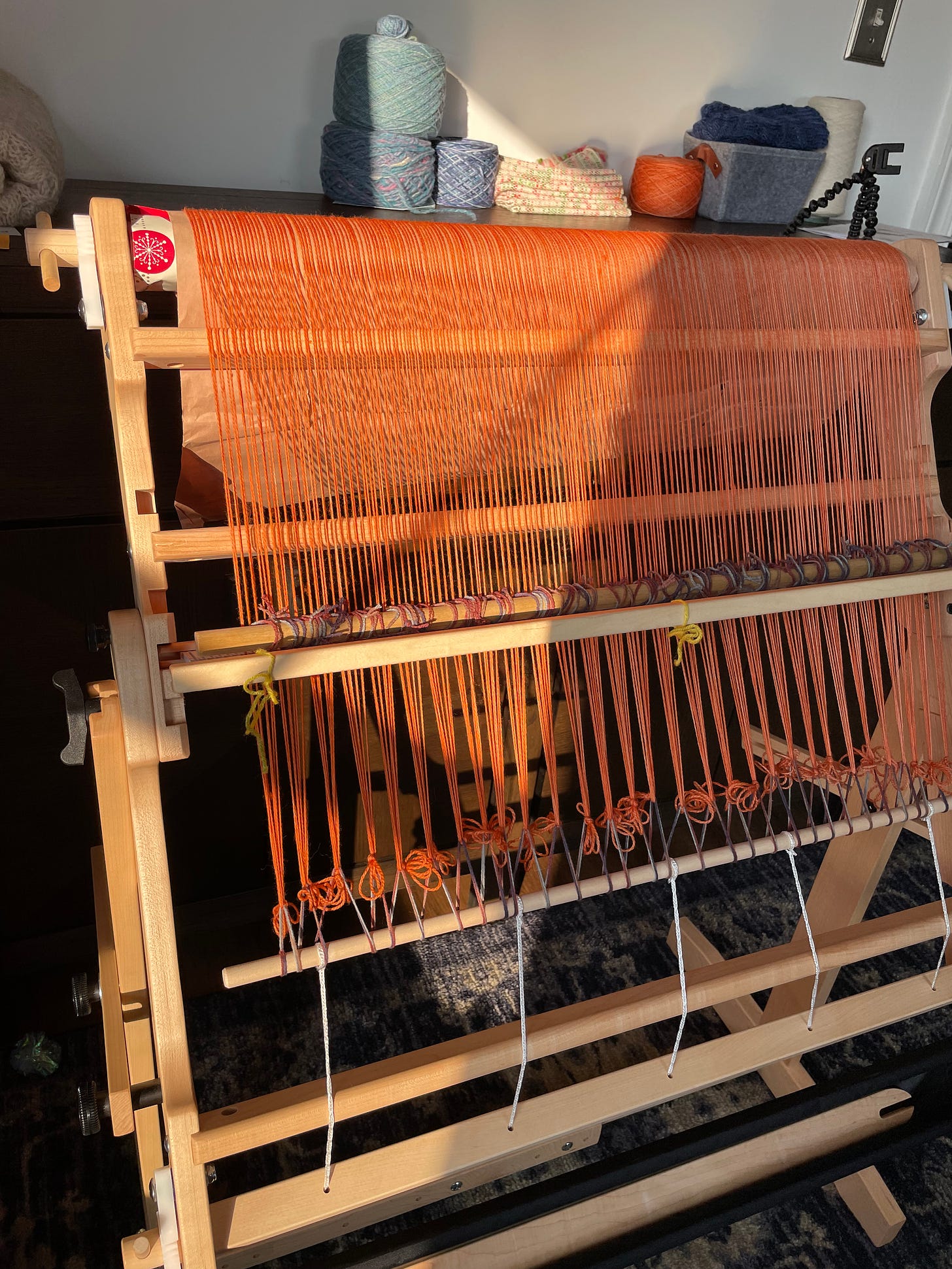 A Flip rigid heddle loom with an orange warp rolled onto the back beam.