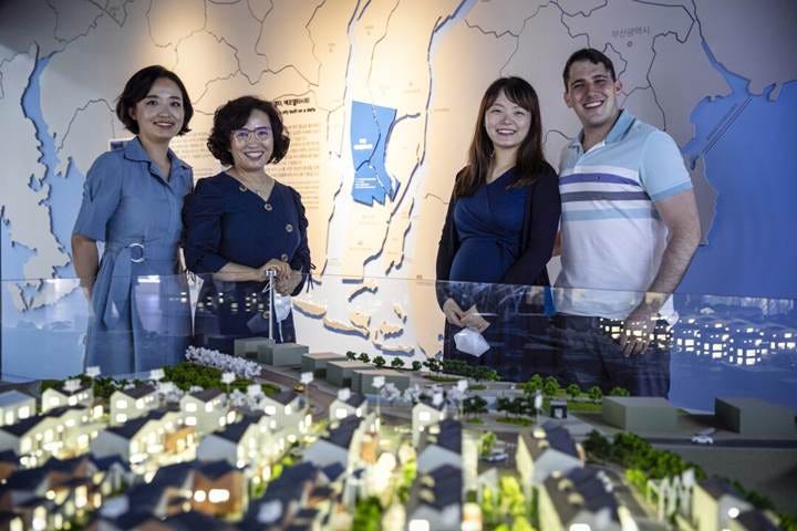 Four people stand around a model of a "smart city