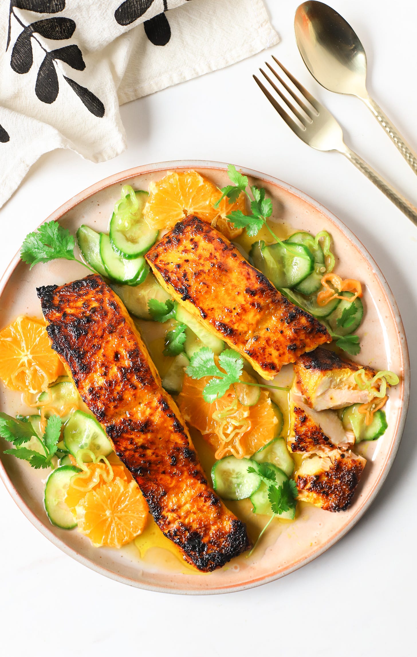 Plate of broiled turmeric-honey salmon with oranges, cucumbers, and habanero peppers