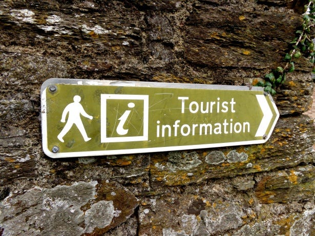 Green sign on rock reading "Tourist Information"