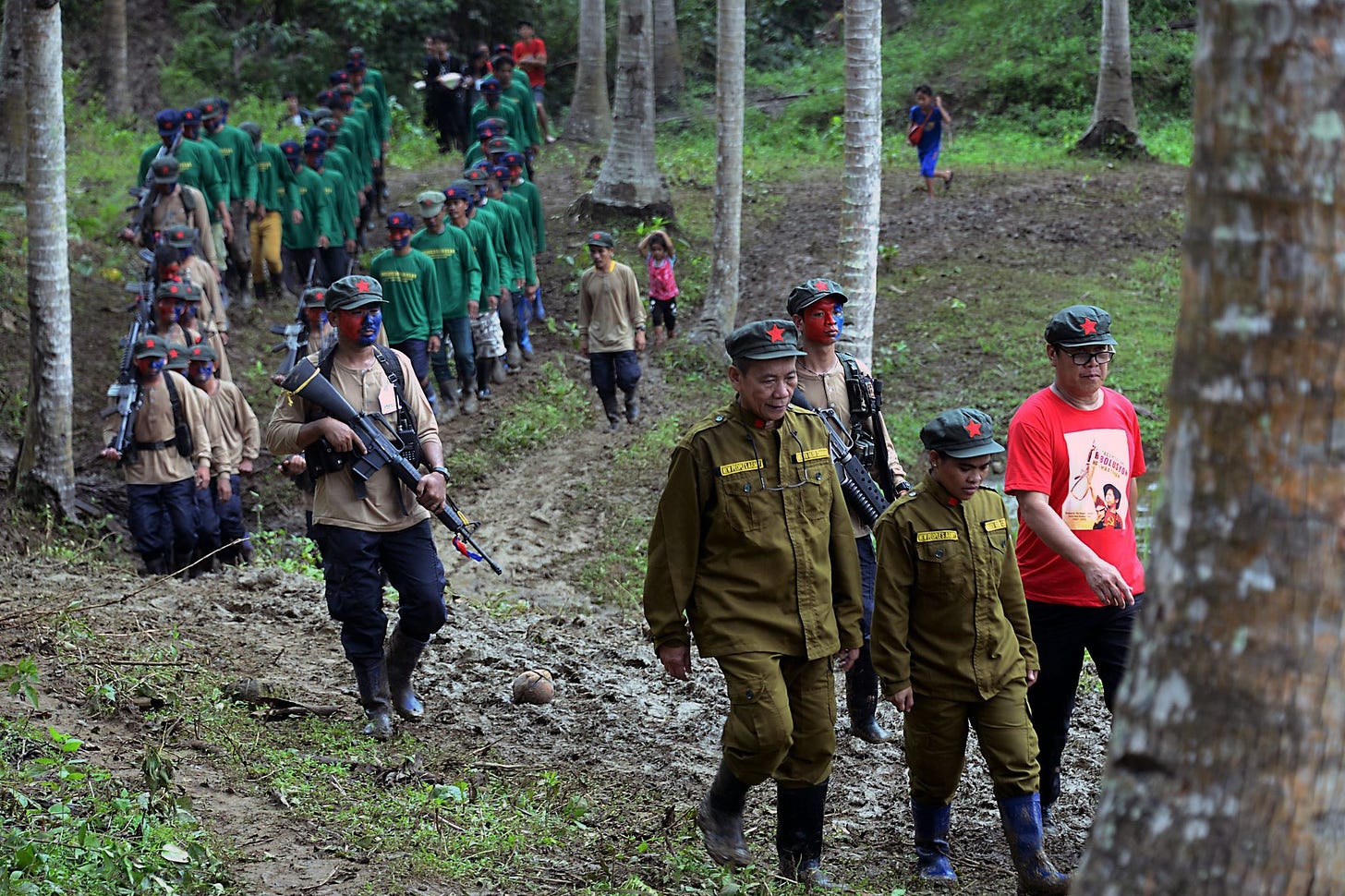Members of the New People's Army donned in various shaeds of green march through a forest