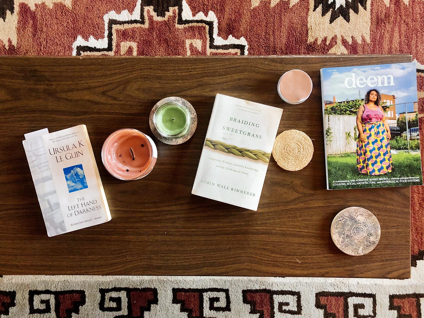 Items artfully scattered across a coffee table include a pink and green candle and three books.