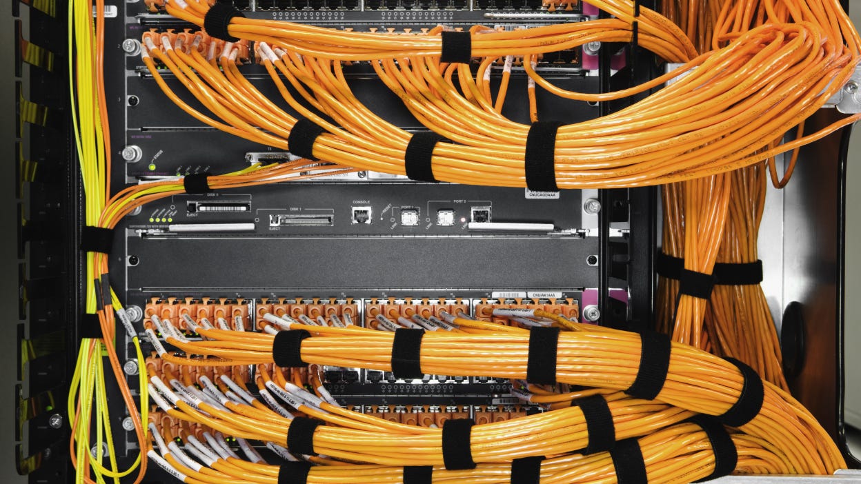 Many orange cables connected to a server box.
