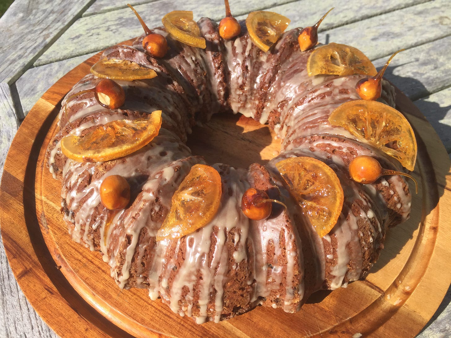 A round bundt cake drizzled with a light glaze, and topped with candied lemon wedges and hazelnuts dipped in caramel.