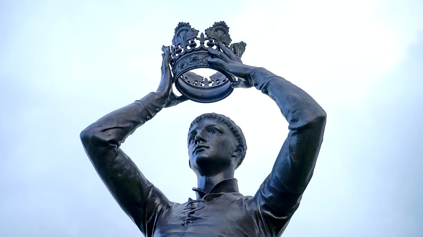 A statue of a man putting a crown on his head.