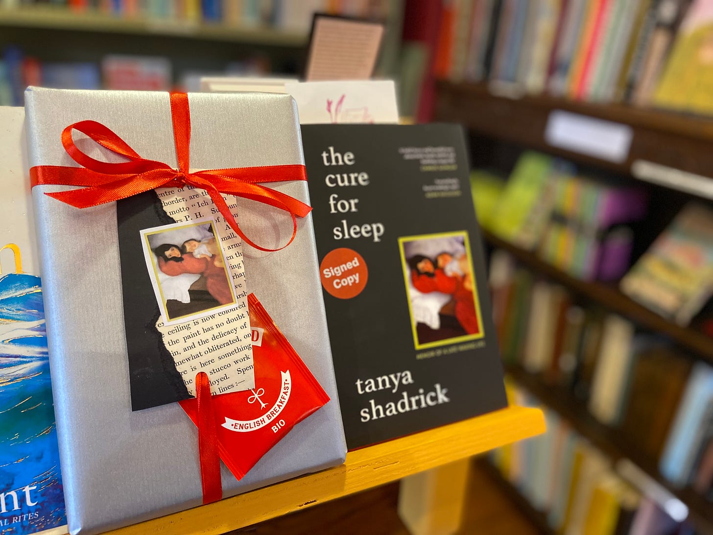 A gift wrapped copy of The Cure For Sleep by Tanya Shadrick on a bookshop shelf at Much Ado Books