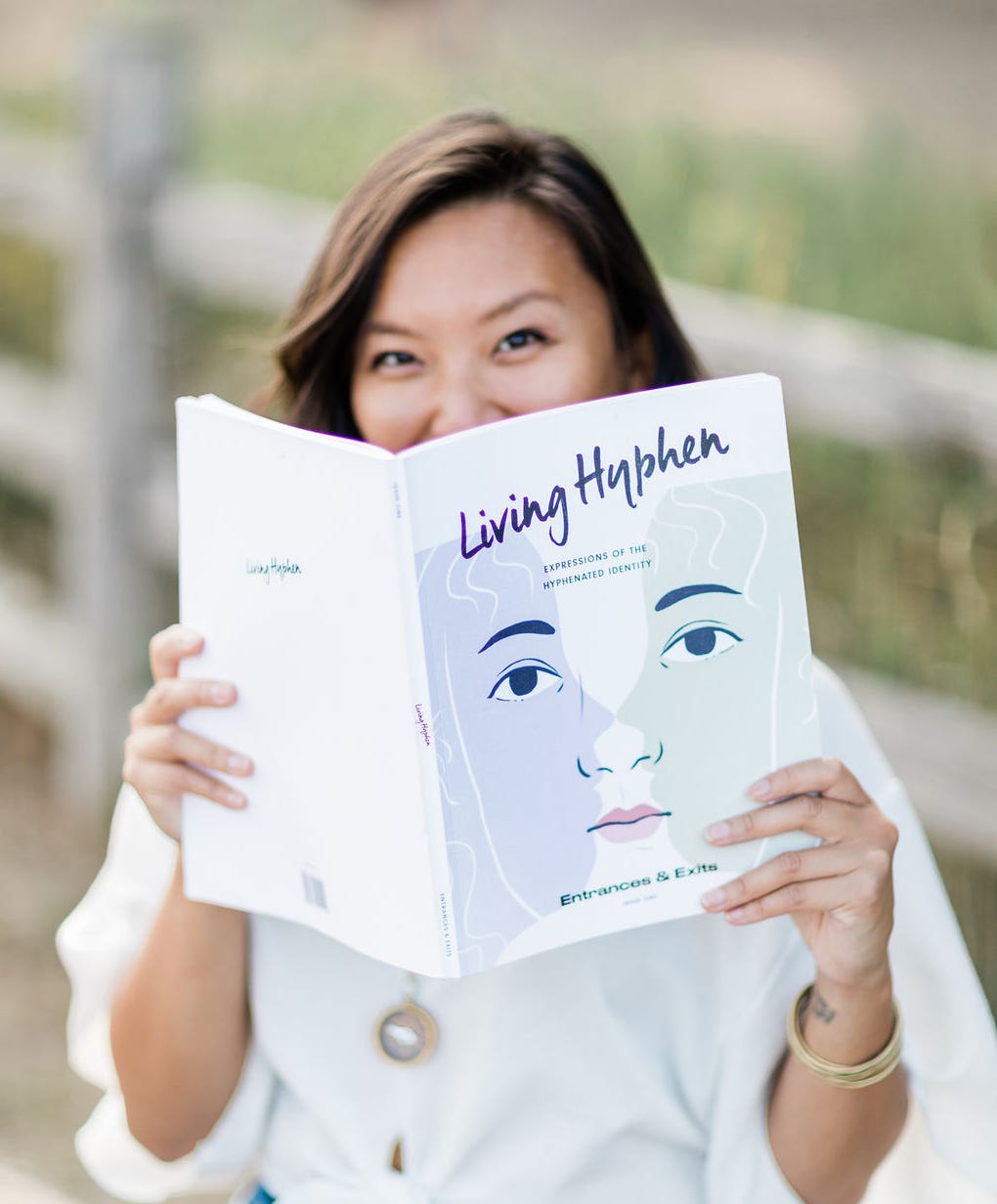 Justine holding up a Living Hyphen magazine up to cover half her face.