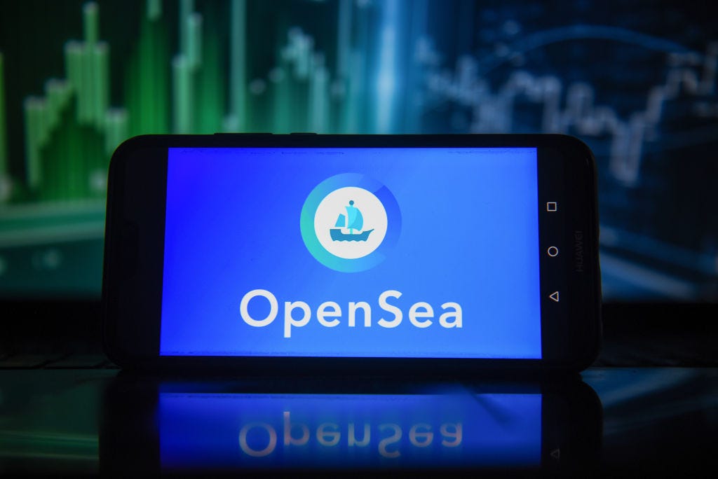 An OpenSea logo is displayed on a smartphone with stock market percentages in the background. (Omar Marques / Getty Images)