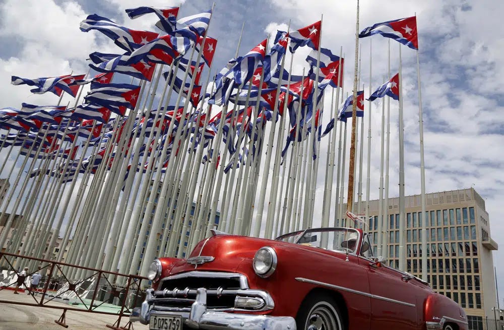 FILE - A classic American convertible car passes beside the United States embassy as Cuban flags fly at the Anti-Imperialist Tribune, a massive stage on the Malecon seaside promenade in Havana, Cuba, July 26, 2015. The United States Embassy in Cuba is opening visa and consular services on Wednesday, Jan 4, 2023. It was the first time since a spate of unexplained health incidents among diplomatic staff in 2017 slashed American presence in Havana(AP Photo/Desmond Boylan, File)