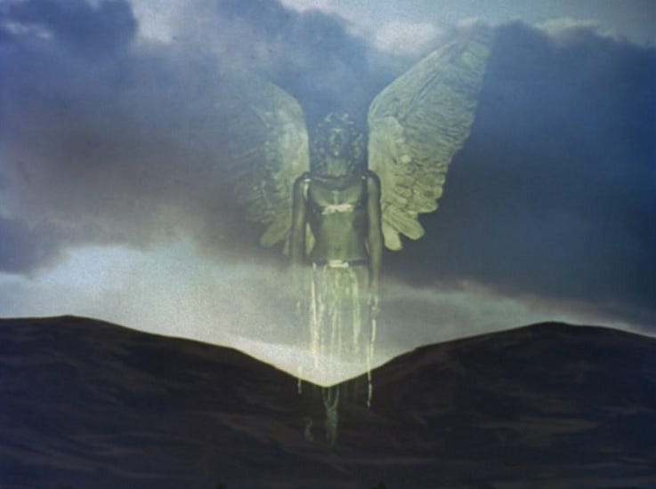 Angel stood in front of two hills in a dark countryside landscape.