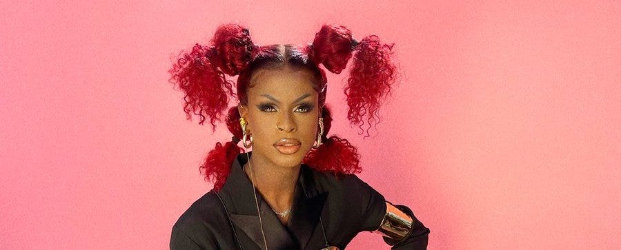 image description: Symone the drag queen looking fierce in red pigtail buns