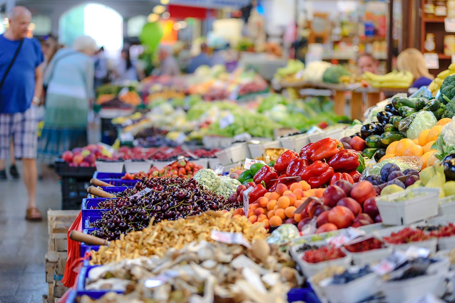 A market stall covered with piles of colorful produce.