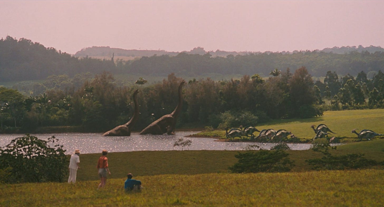 Three people, an old man and a young couple, observe dinosaurs bathing and drinking in a lake