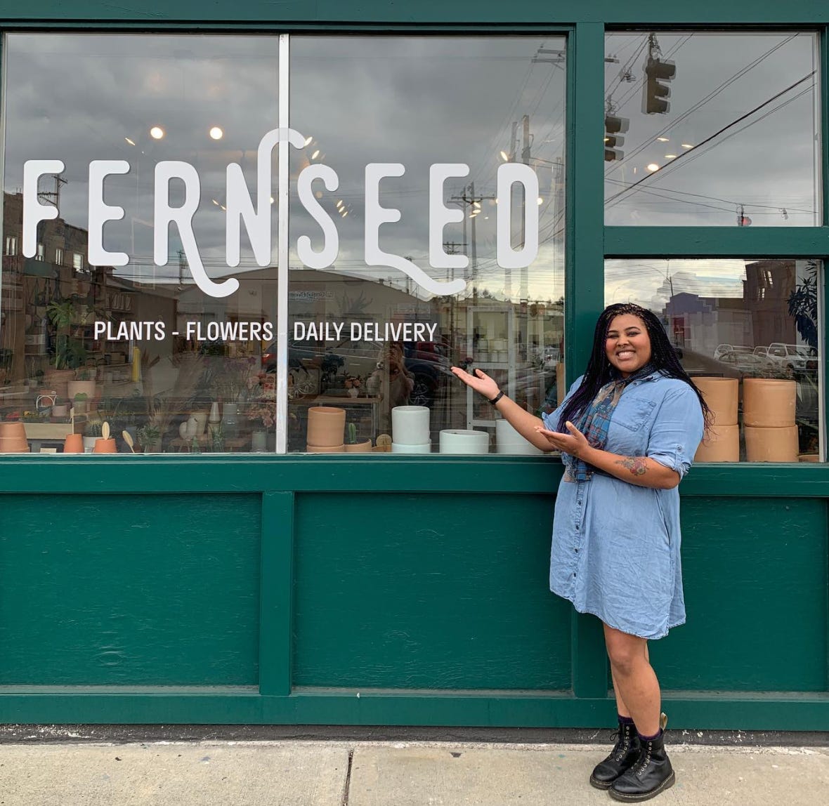 person smiling standing in front of fernseed shop