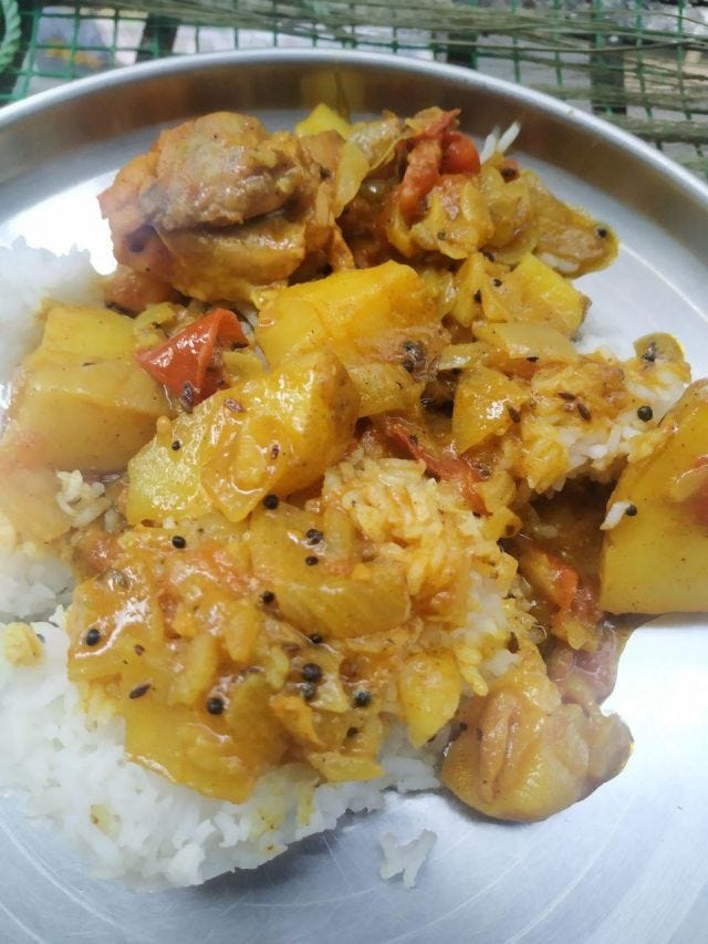 A plate of rice with potato and chicken pieces