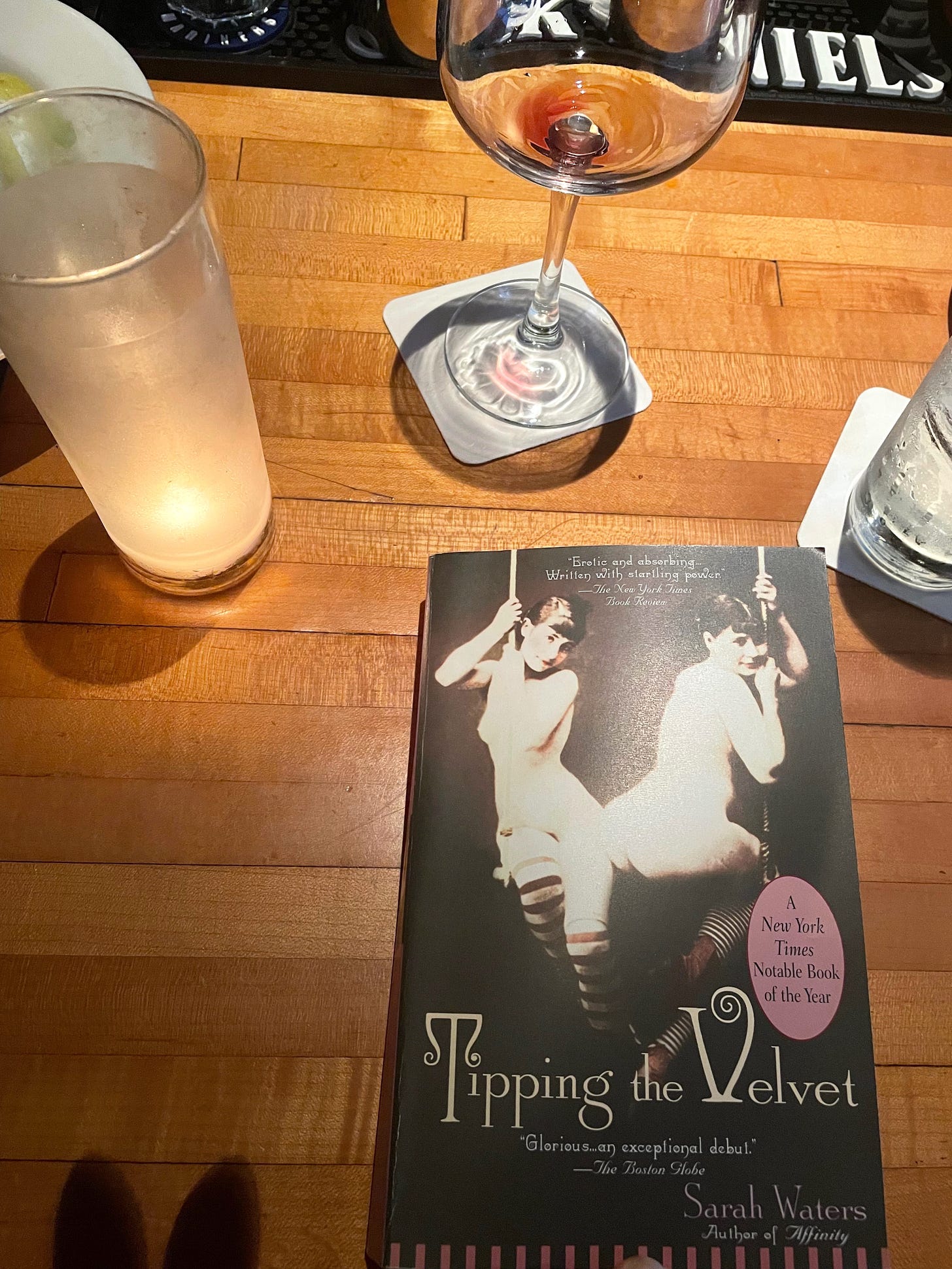 image of book "tipping the velvet" next to empty wine glass, water glass, and a candle