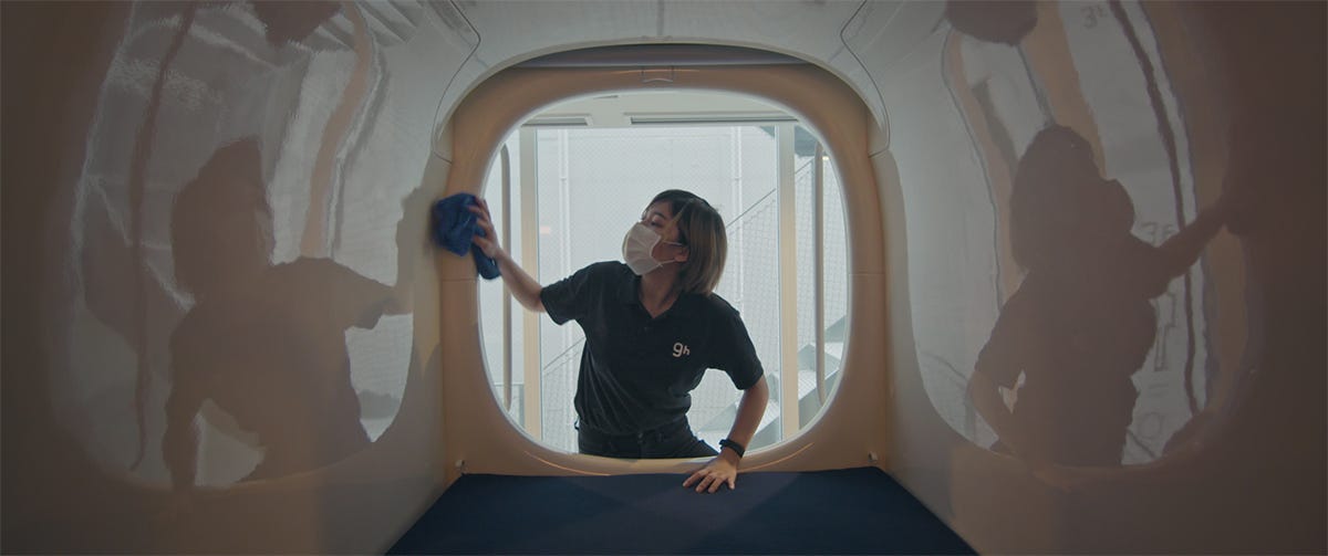 A woman cleans the inside of a capsule in Tokyo. Still from When We Live Alone, 2020. © CCA.