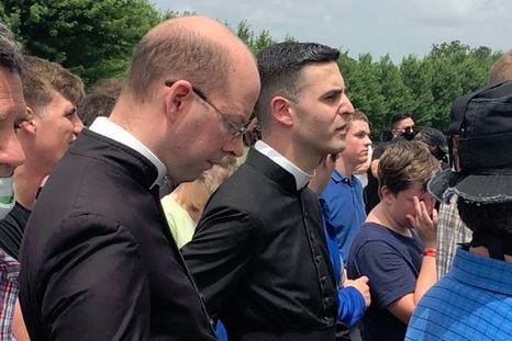 Holy priests, reportedly of the Institute of Christ the King, provide clerical guidance to Catholics praying for the preservation of a saintly statue.