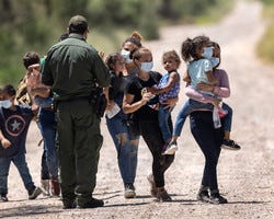 A U.S. Border Patrol agent instructs immigrant families as they prepare to board transport to a processing center after crossing the U.S.-Mexico border.