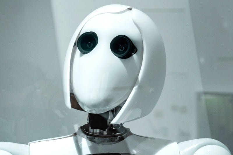 Imagem mostra rosto, pescoço e parte do busto de um robô humanóide chamado “AILA”, com traços (cabelos) femininos e olhos que aparentam ser câmeras.