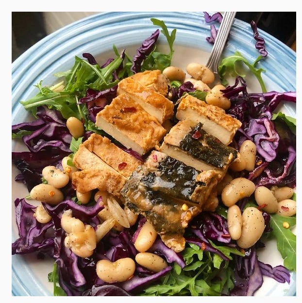 A vegan meal of tofu on a bed of salad and broadbeans