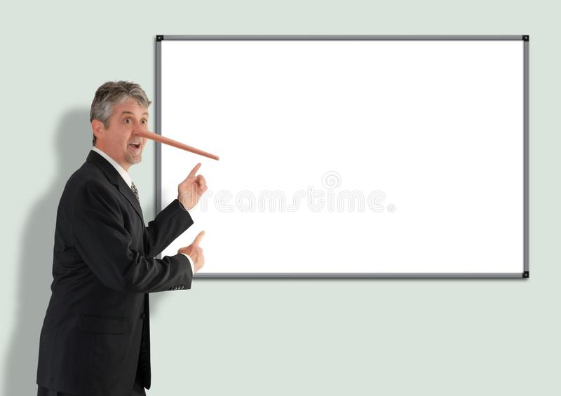 Lying dishonest businessman with growing Pinocchio nose pointing to blank white board. Where you can put your message stock photo