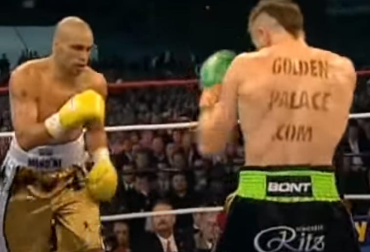 An image from a televised boxing match where one boxer has an ad written on their back.