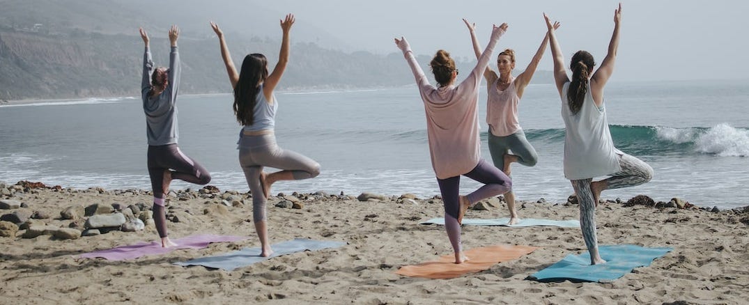 Women doing yoga on the beach.