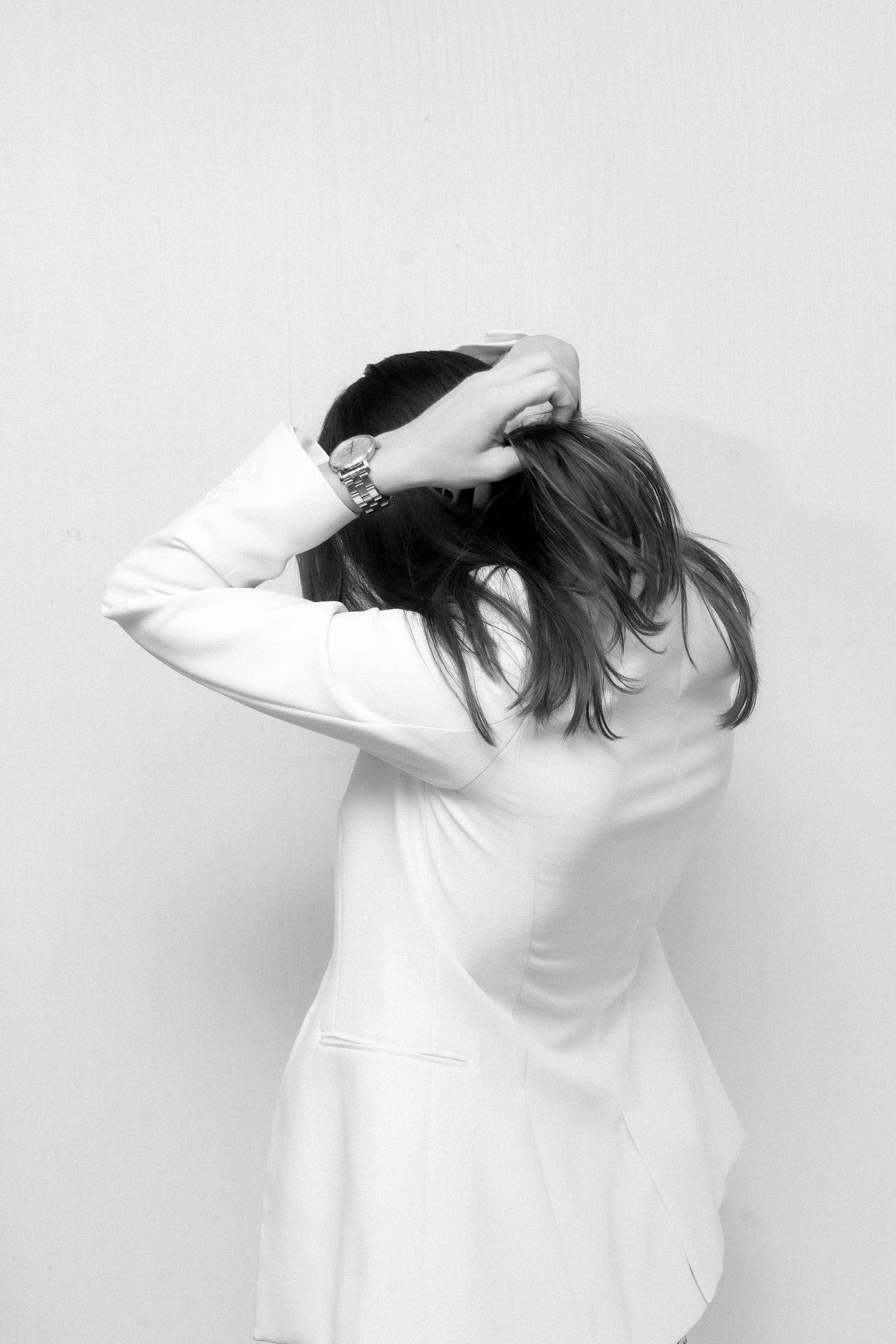 Image of a woman in a white suit with her hands over her head, in a gesture of overwhelm. Free image from Upsplash