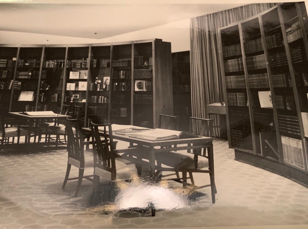 Black and white photo of the Sterling Morton library, with rounded bookcases and library tables on a hexagonal tile floor.