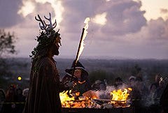 A neopagan person is holding a torch to celebrate Samhain