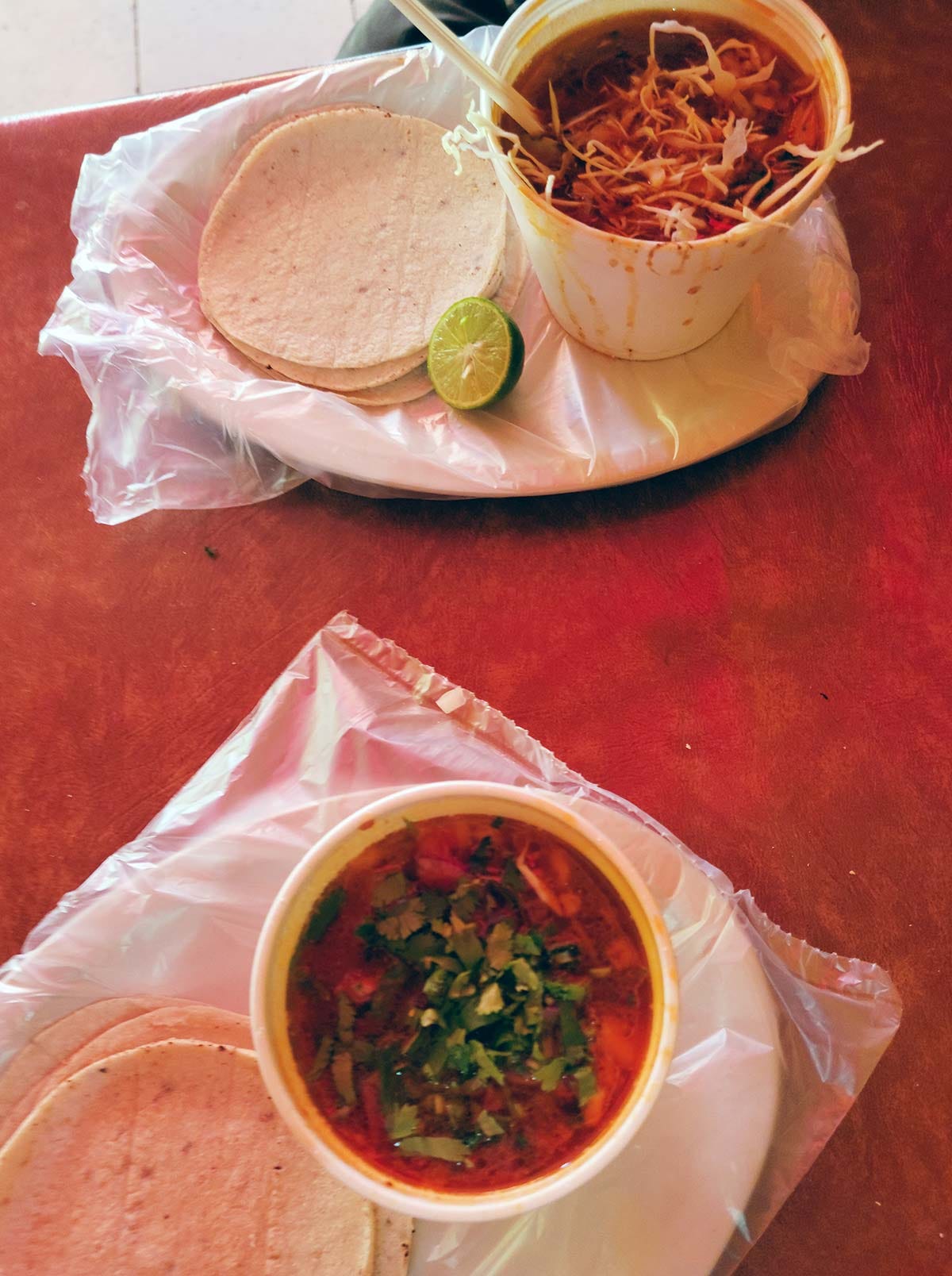Two bowls of Sonoran barbacoa in its broth, with tortillas. 