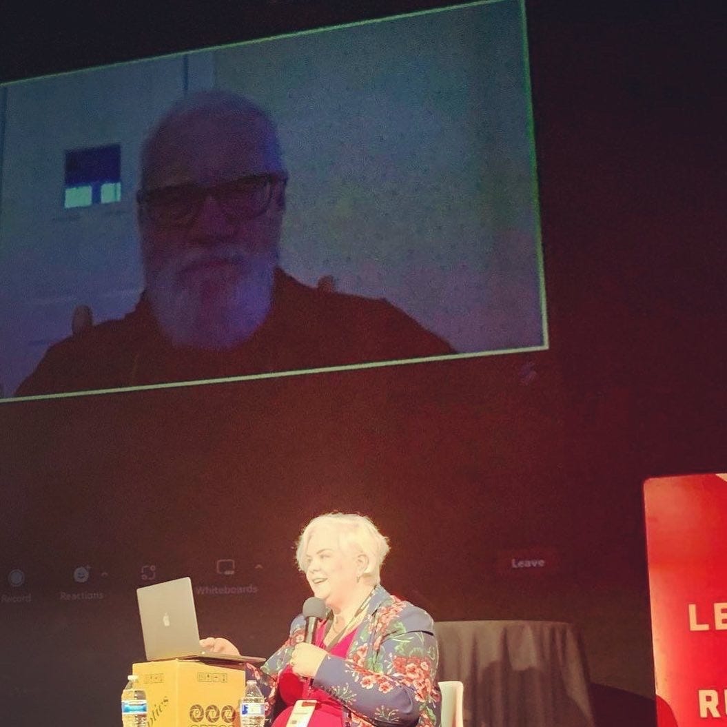 Caissie onstage, speaking to David Letterman, who is projected on a big screen to an auditorium, at the Catalyst Content Festival in Duluth, MN.