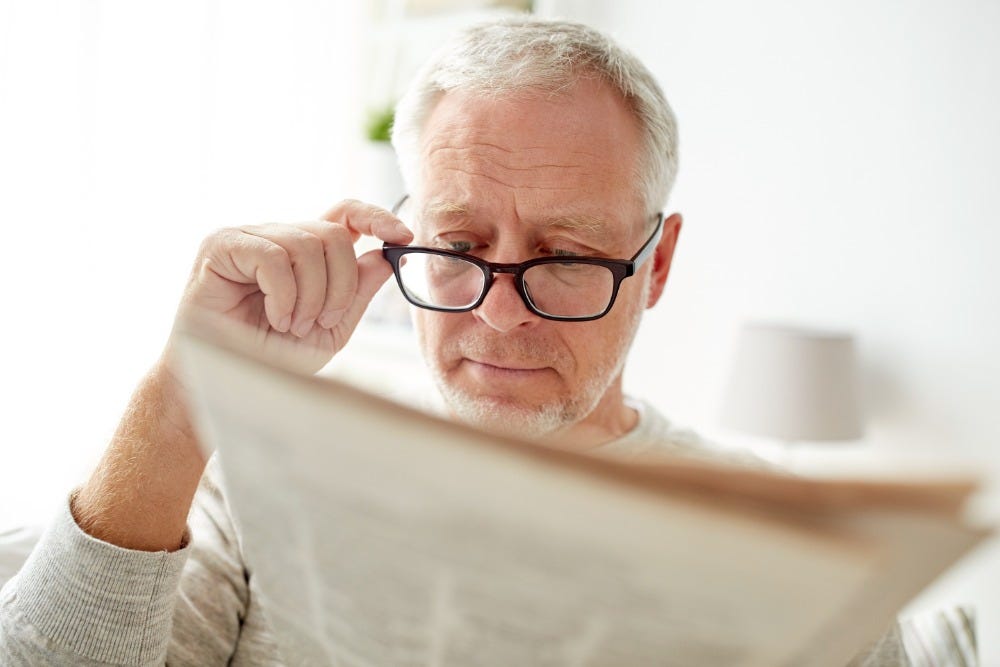 Man with glasses reading newspaper
