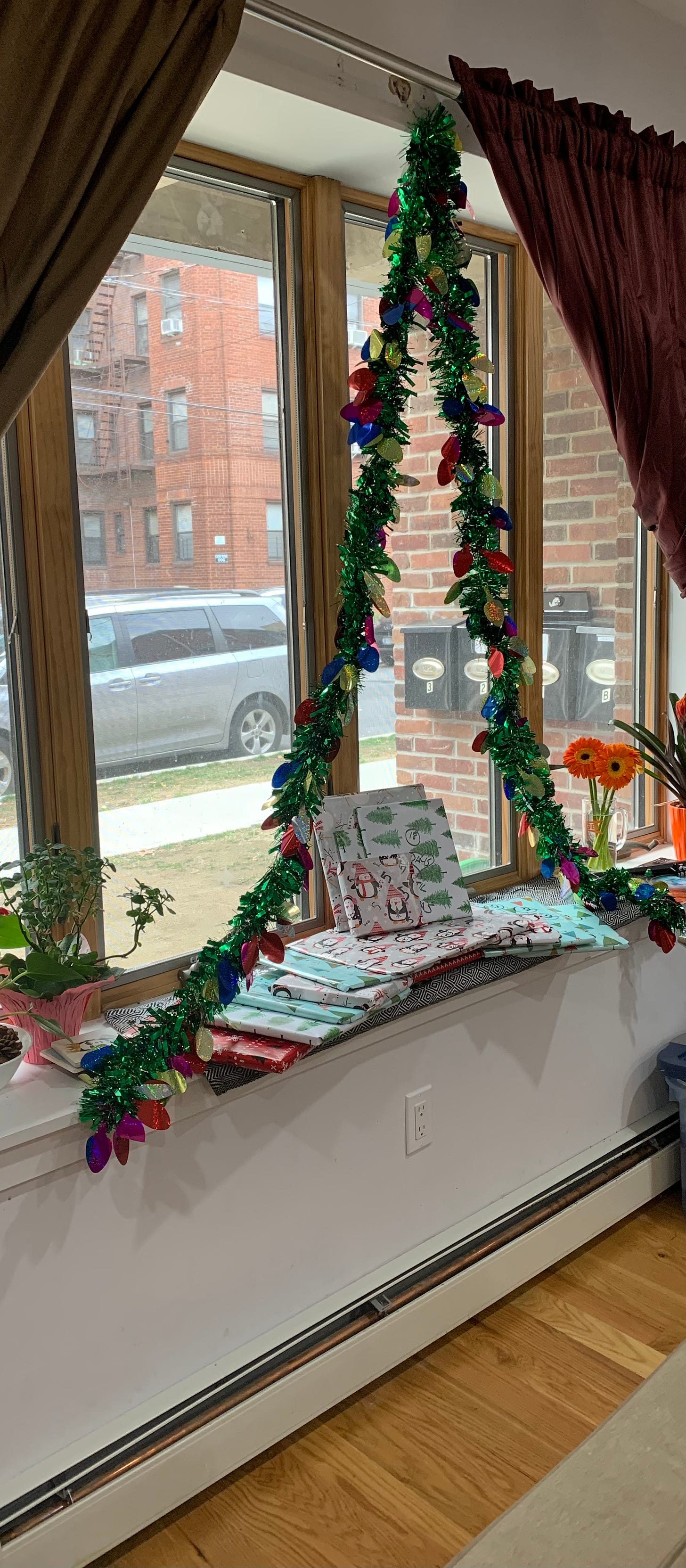 A bay window with books wrapped underneath a tinsel tree