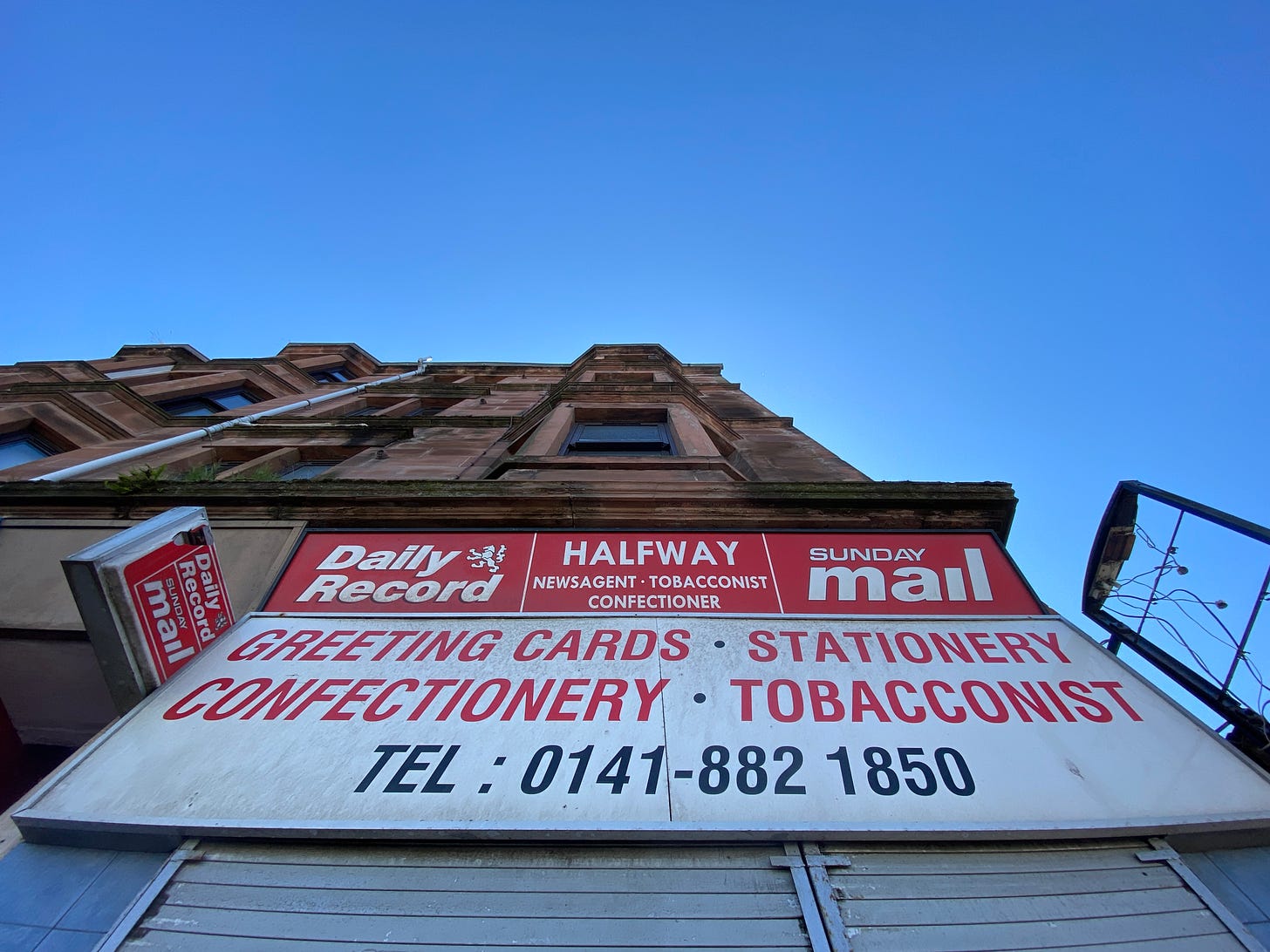 Newsagents and tenement flat with sign saying Halfway