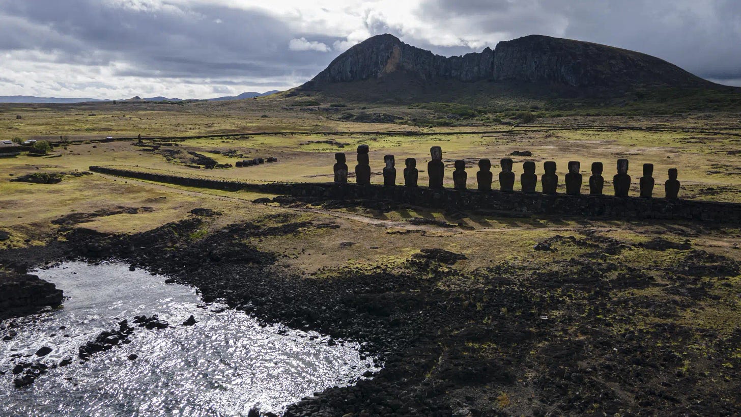 Moai statues stand on Ahu Tongariki near the Rano Raraku volcano, top, on Rapa Nui, or Easter Island, Chile, Sunday, Nov. 27, 2022. Each monolithic human figure carved centuries ago by this remote Pacific island's Rapanui people represents an ancestor. (AP Photo/Esteban Felix)