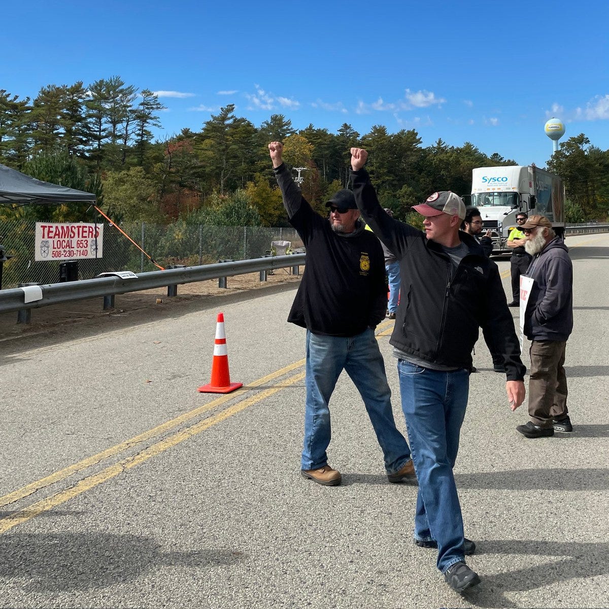 Two Teamsters raise their fists after a truck on nearby Route 44 honked in support