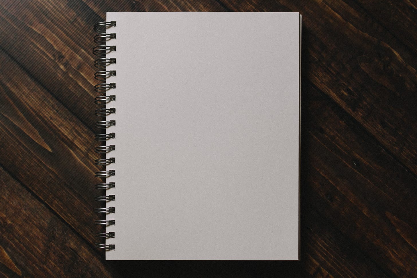 White notebook on brown wooden table.