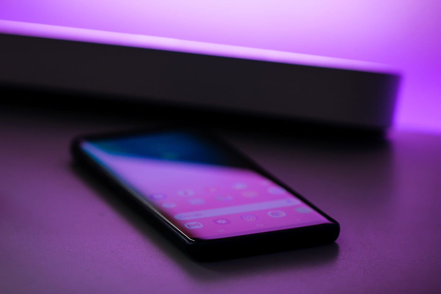 picture of a mobile phone on a surface awash with purple light