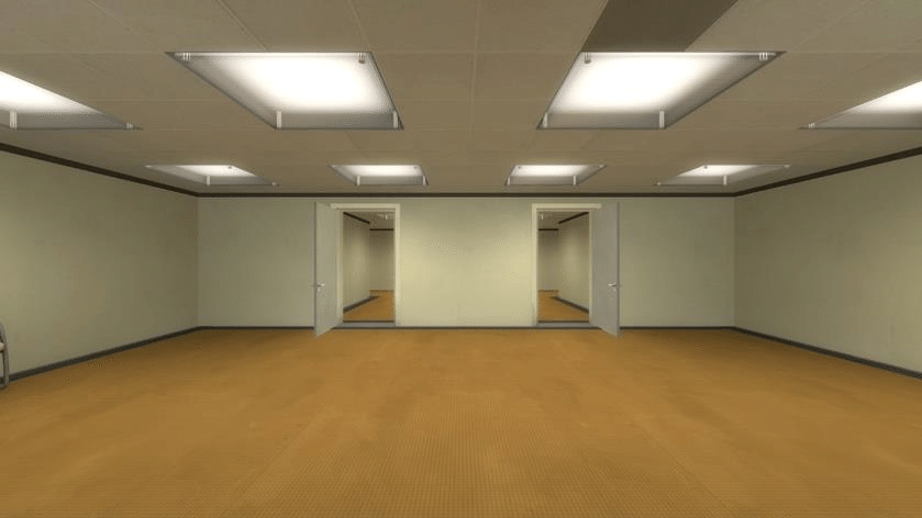A large, empty office room with brown carpet, beige walls, and flourescent lighting. Two open doors sit across from the viewer in the middle of the opposite wall.