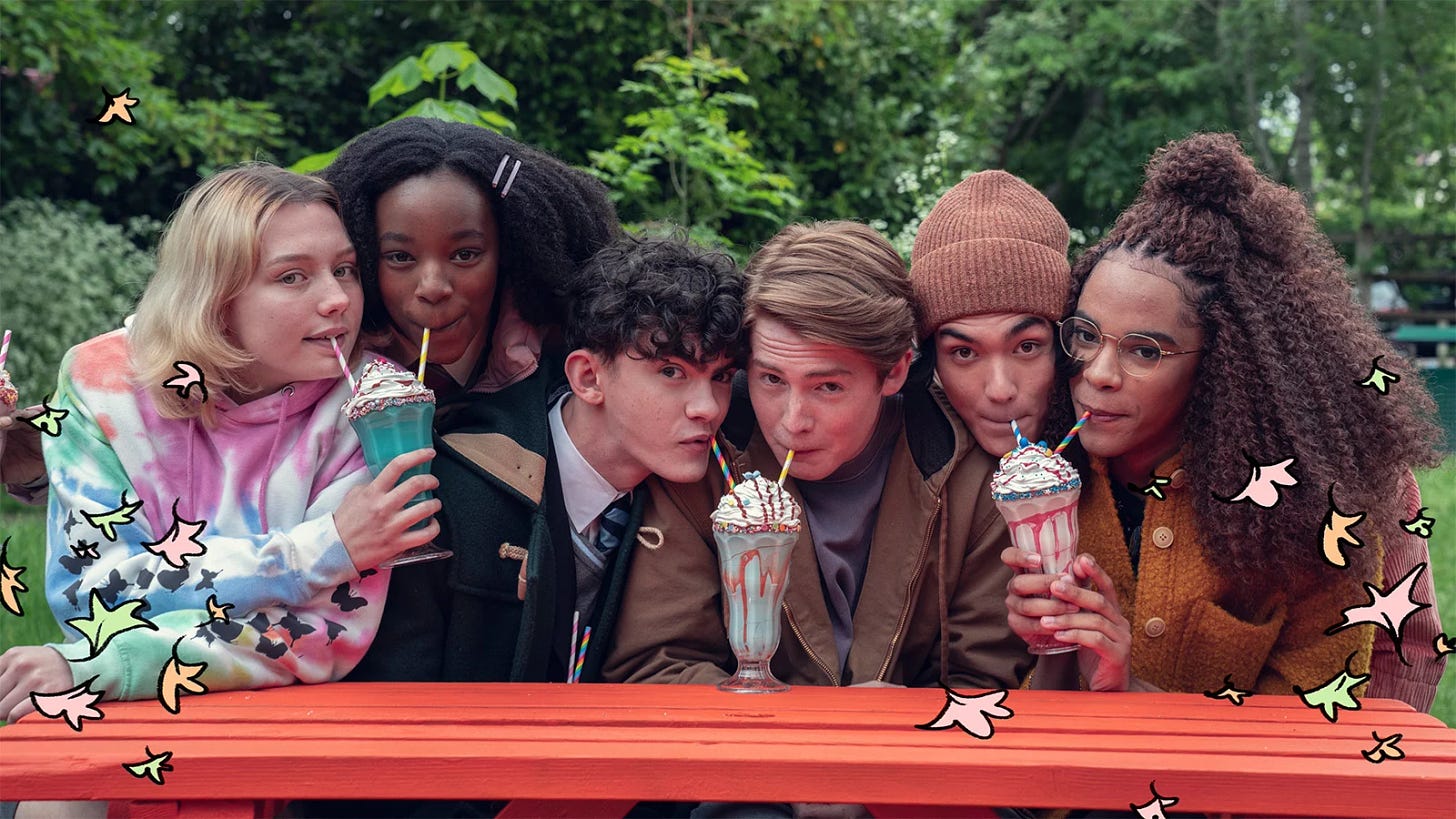 six young actors, a white blonde with shoulder length hair, a black girl with long curly hair, two white boys, one curly and dark haired, the other blonde, an asian man and a black trans woman with long curly hair and wearing glasses are paired up and sipping milkshakes