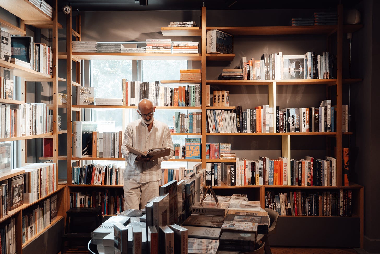 a man reading a book while surrounded by books on shelves