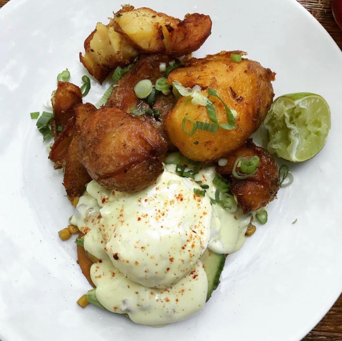 Photo of Longman & Eagle's elote eggs benedict. View of a plate from above. Roasted potatoes and a poached egg over a corn cake.