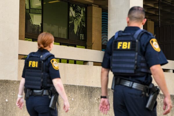 F.B.I. police officers wearing uniforms and body armor walking past the bureau’s headquarters in Washington.